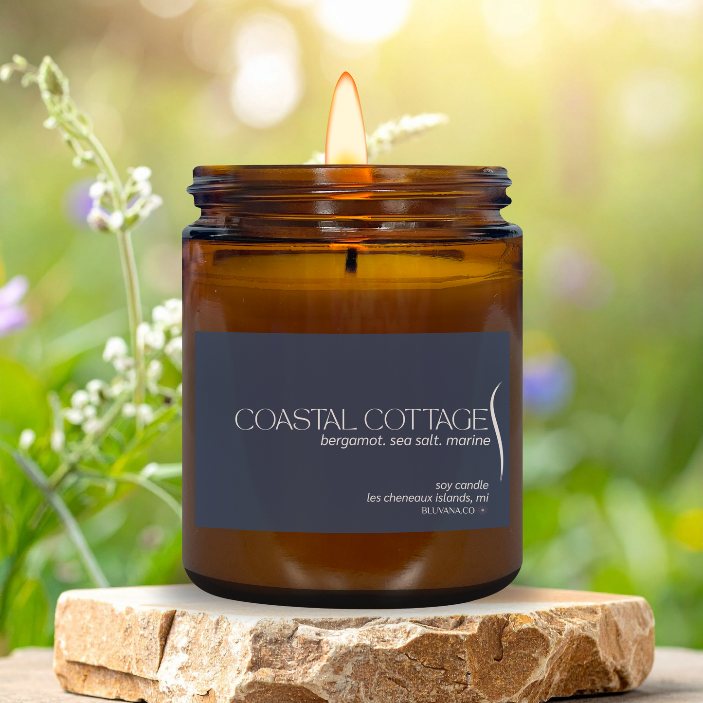 Coastal Cottage candle in an amber jar with a label, set against a natural background.
