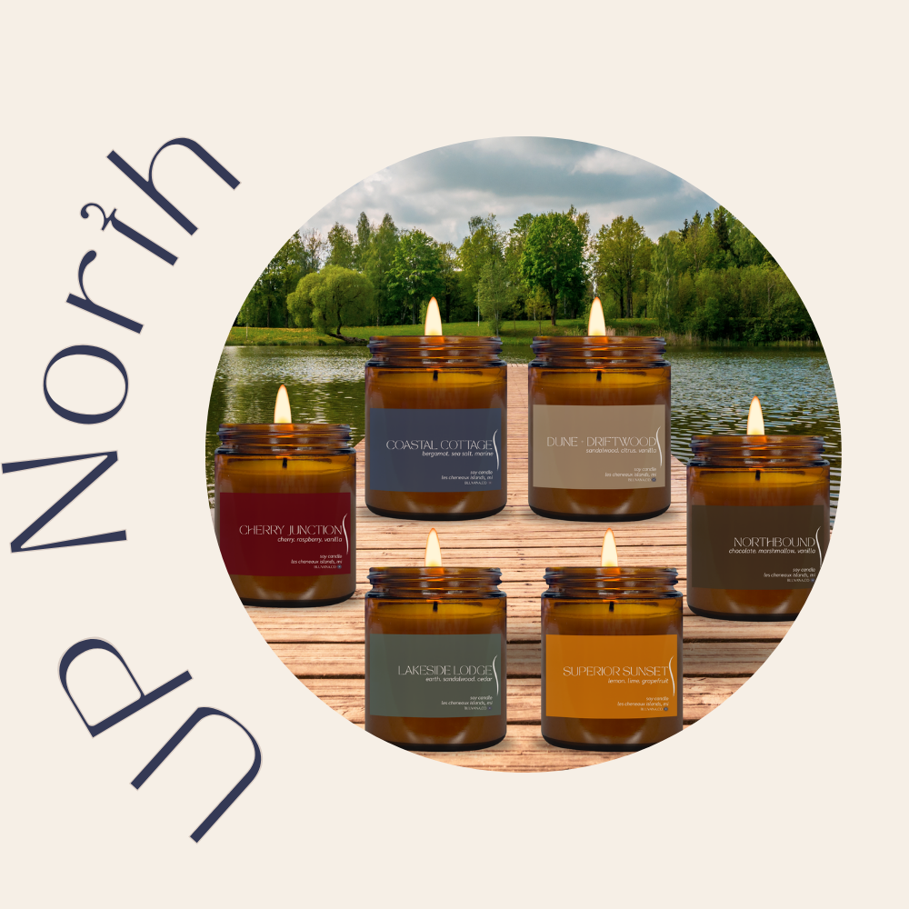 image of 6 candles in amber glass jars with colored labels depicting various names and scents