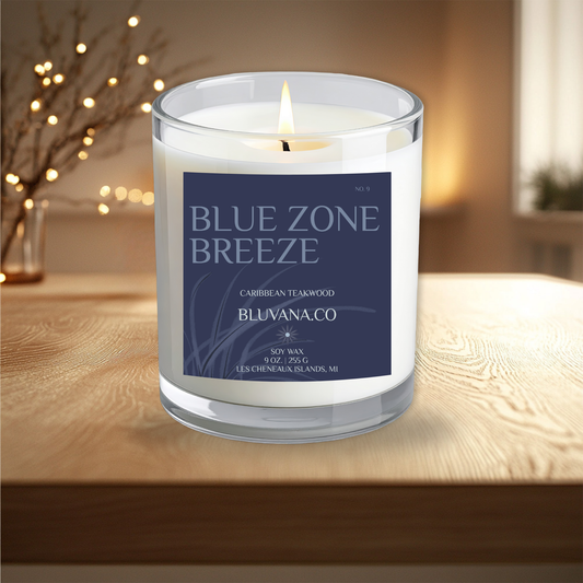 Candle with a label reading 'Blue Zone Breeze' by Bluvana Co. on a wooden surface.