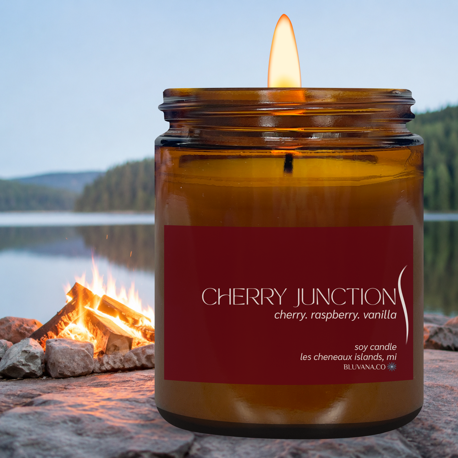 Candle in an amber jar with a red label by a campfire by a lake