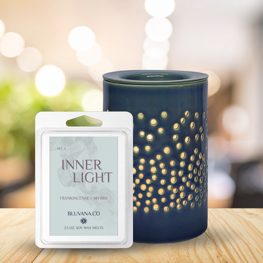 Blue wax warmer with decorative design next to a 'Inner Light' wax melt packaging on a wooden surface.