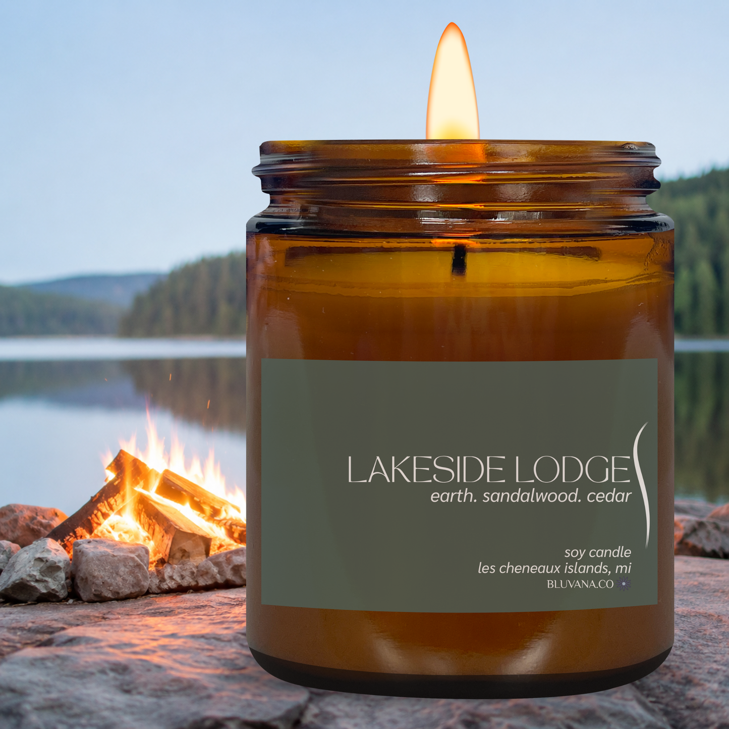 Candle in an amber jar labeled 'Lakeside Lodge' with a campfire and lake in the background