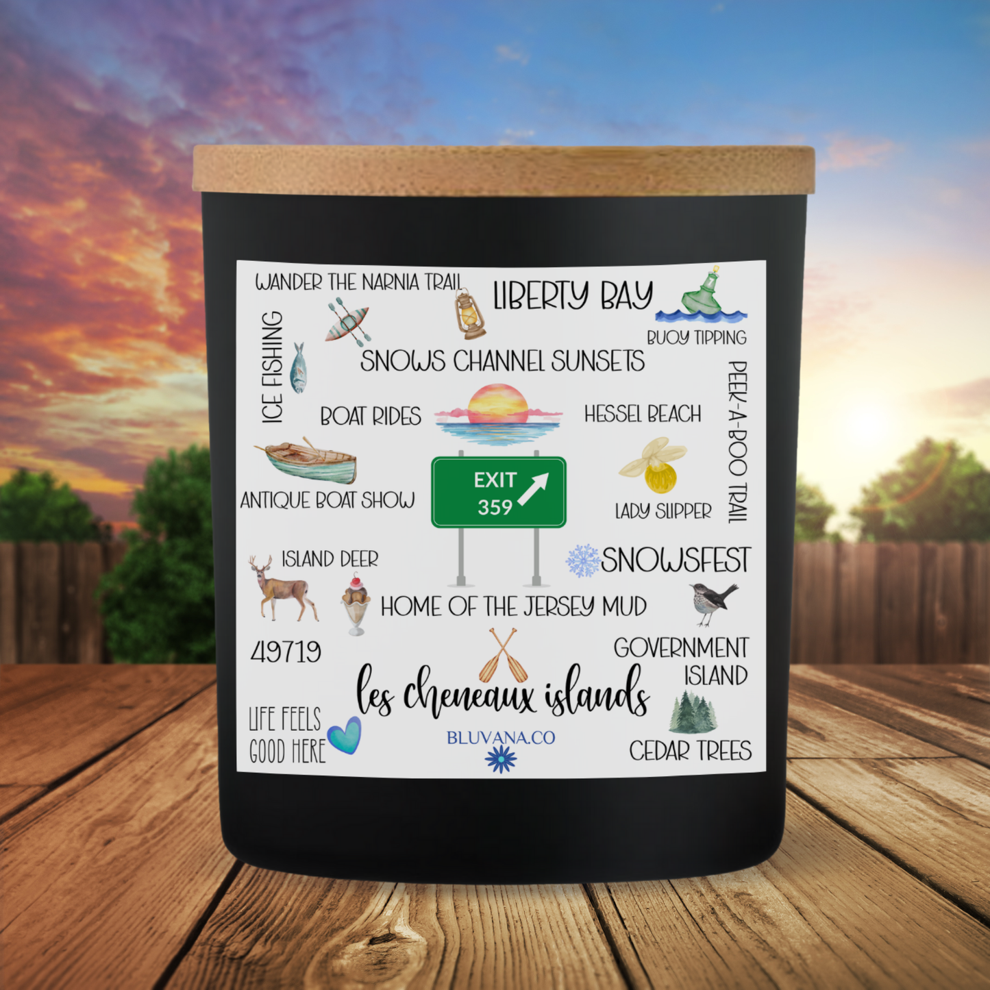 Black candle with a scenic design on a wooden surface with a sunset background