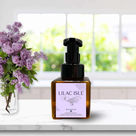 Bottle of Lilac Isle product with a vase of lilacs on a white surface.