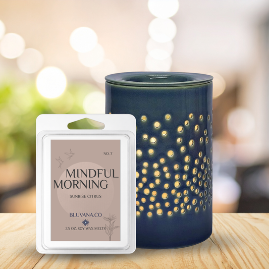 Scented wax melt packaging labeled 'Mindful Morning' next to a blue diffuser with a blurred background