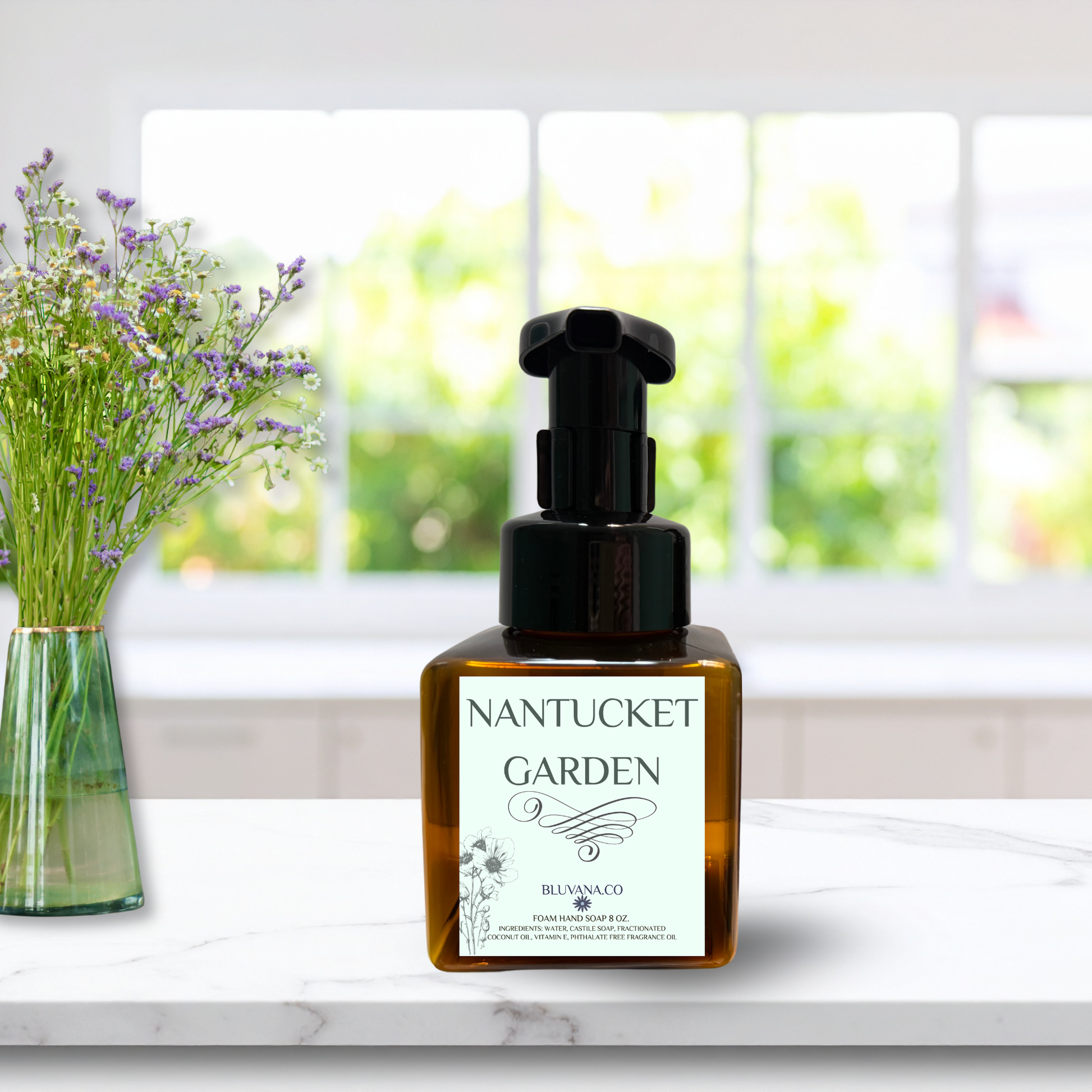 Foam Hand Soap pump bottle with green label that reads 'Nantucket Garen', sitting on a white kitchen counter with a green vase of wildflowers in the background. 