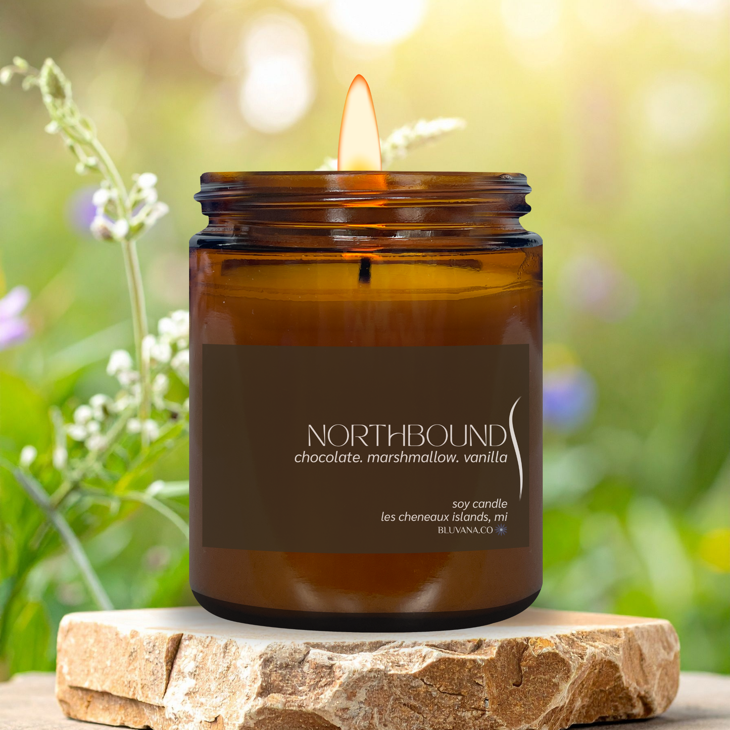 Brown candle in a glass jar labeled 'Northbound' on a stone surface with a natural background