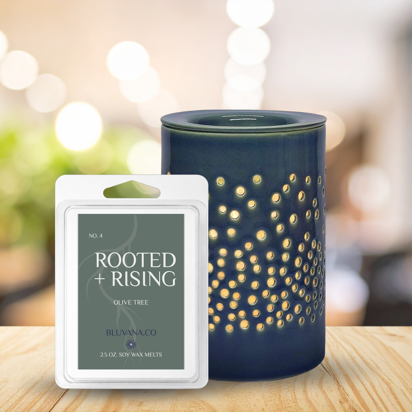 Blue candle with decorative pattern and 'Rooted + Rising' wax melt packaging on a wooden surface.