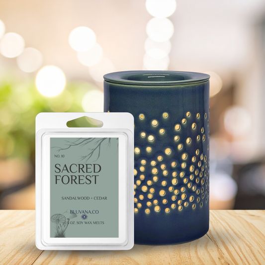 Blue wax warmer with 'Sacred Forest' wax melt packaging on a wooden surface.