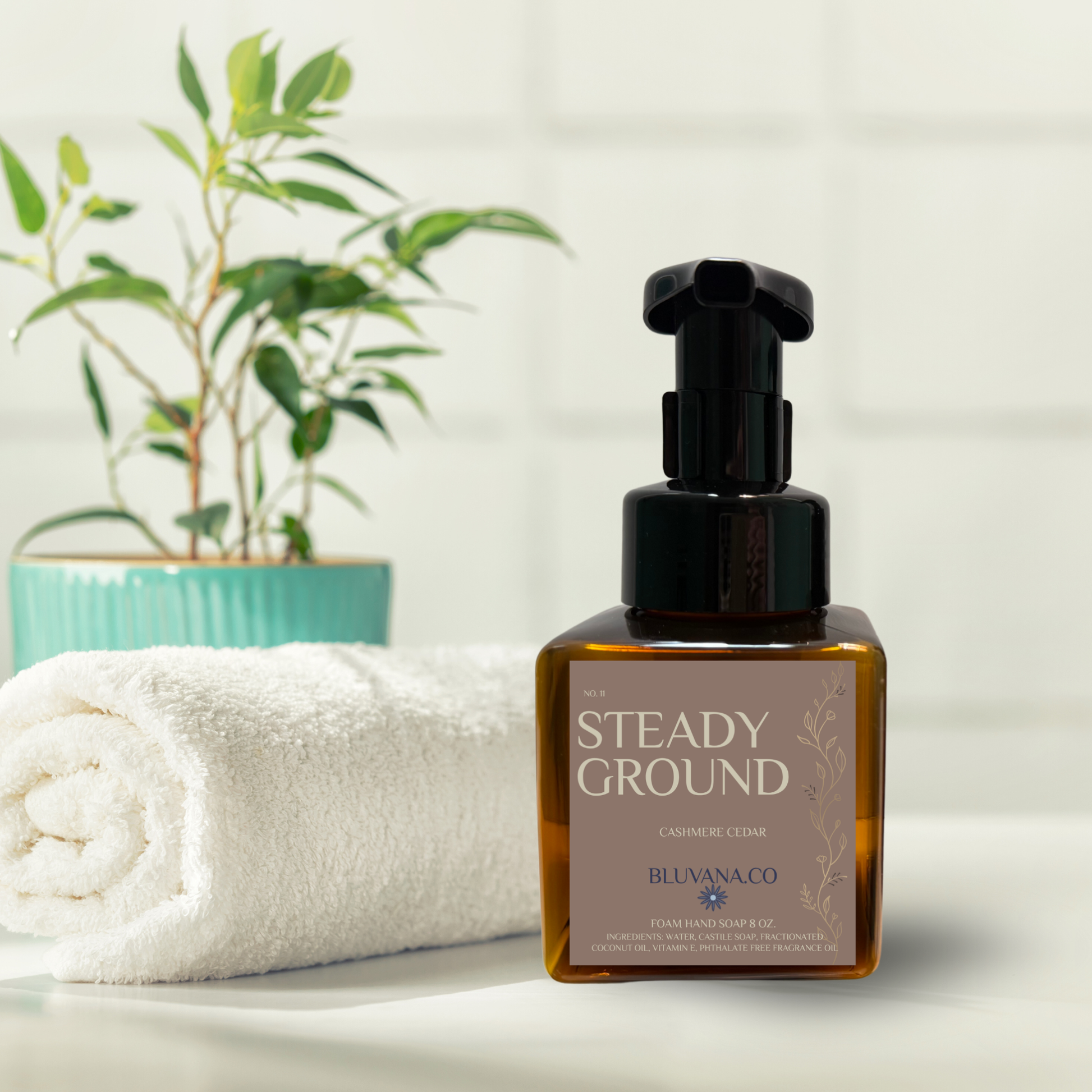 Bottle of 'Steady Ground' cream on a white surface with a plant in the background