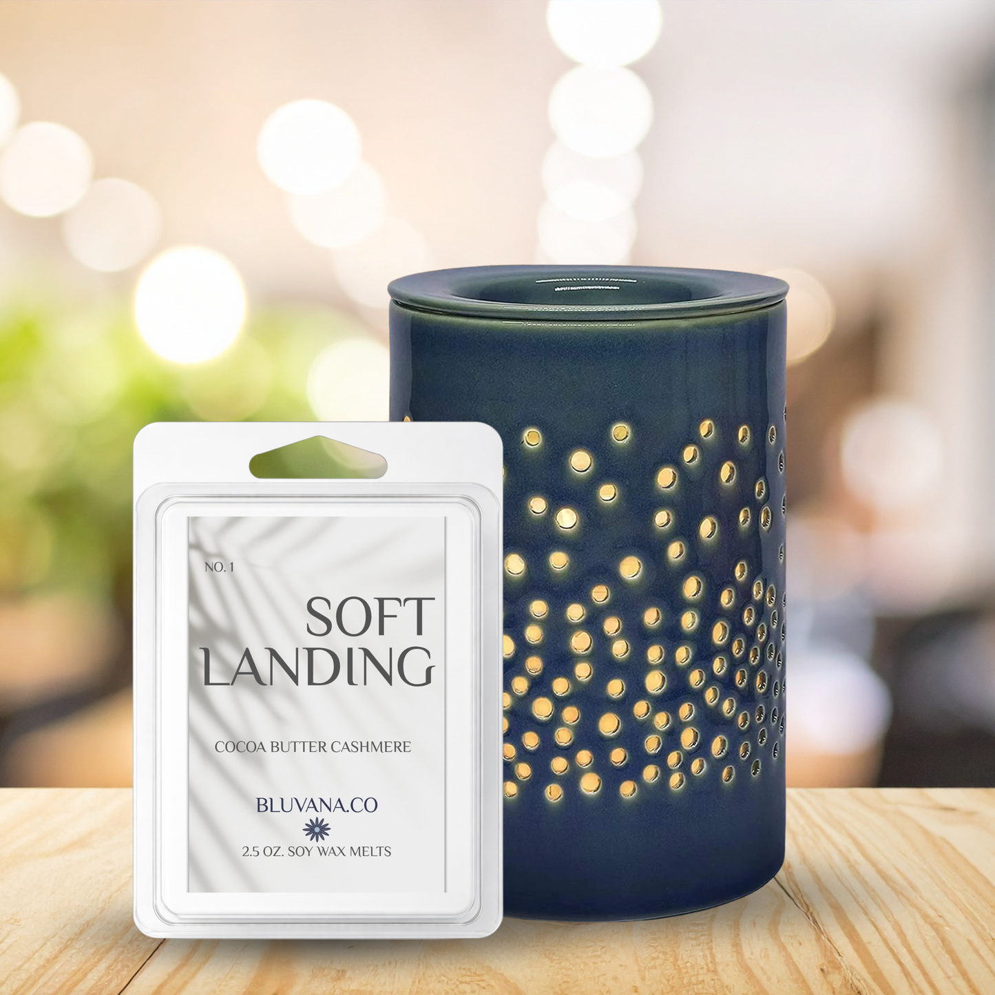 Blue wax melt burner with decorative design next to a 'Soft Landing' wax melt package on a wooden surface.