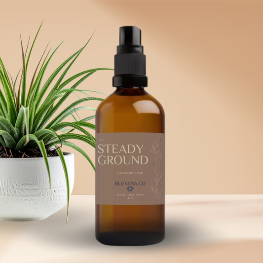 Brown spray bottle labeled 'Steady Ground' by Bluvanaco with a plant on a beige background