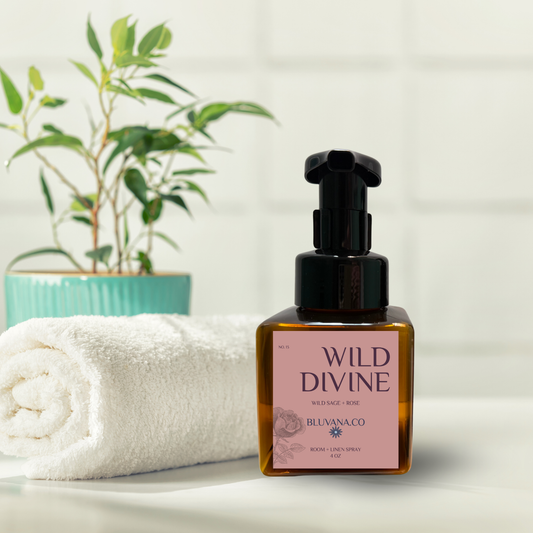 Bottle of 'Wild Divine' product by Bluvana Co on a white surface with a towel and plant in the background.